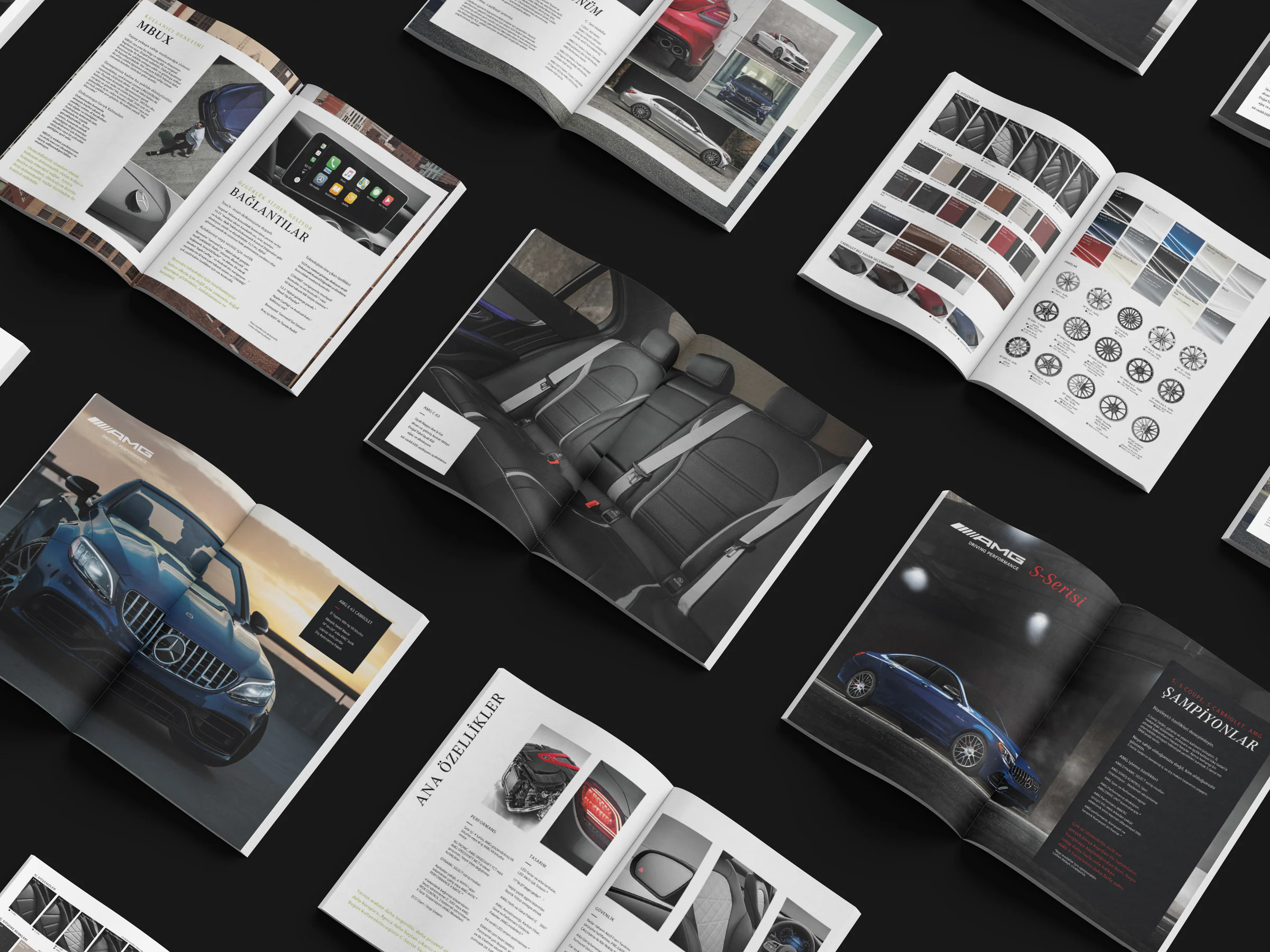 Open catalogue spreads in a diagonal grid on black: MBUX and connectivity, rear-seat interior, trim and wheel options, blue AMG cars.