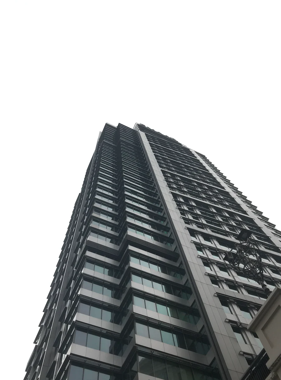 Original photo: a high-rise shot from street level against a white overcast sky, with an ornate street lamp near the right edge.
