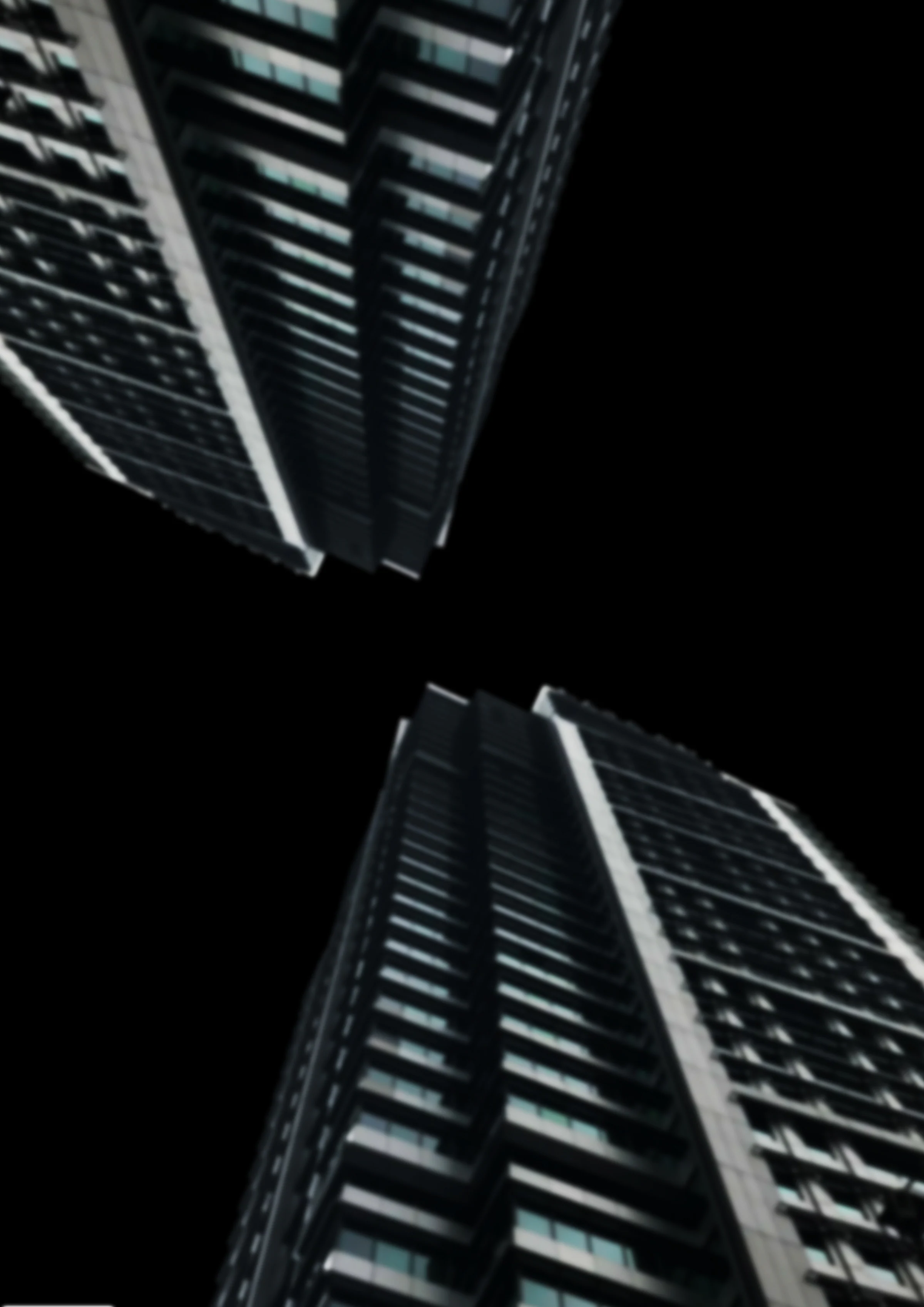 Edited image: two blurred cutouts of the same high-rise, one upside down, set on a diagonal and facing each other across a black gap.