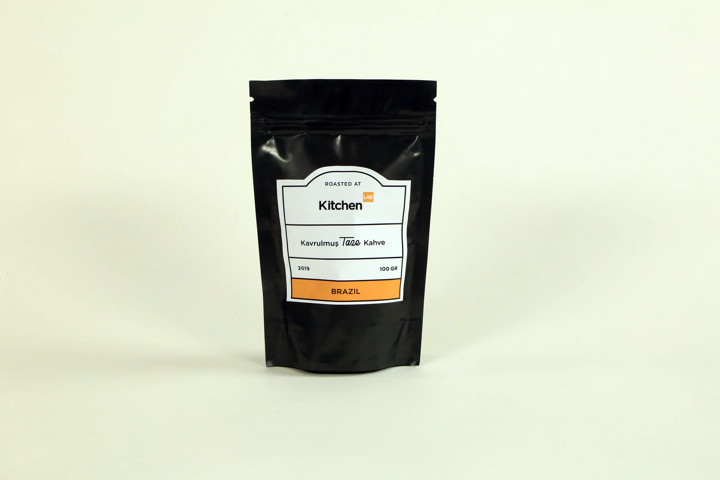 Black stand-up coffee pouch with the KitchenLAB front label, marked Brazil, 100 GR, on a cream backdrop.