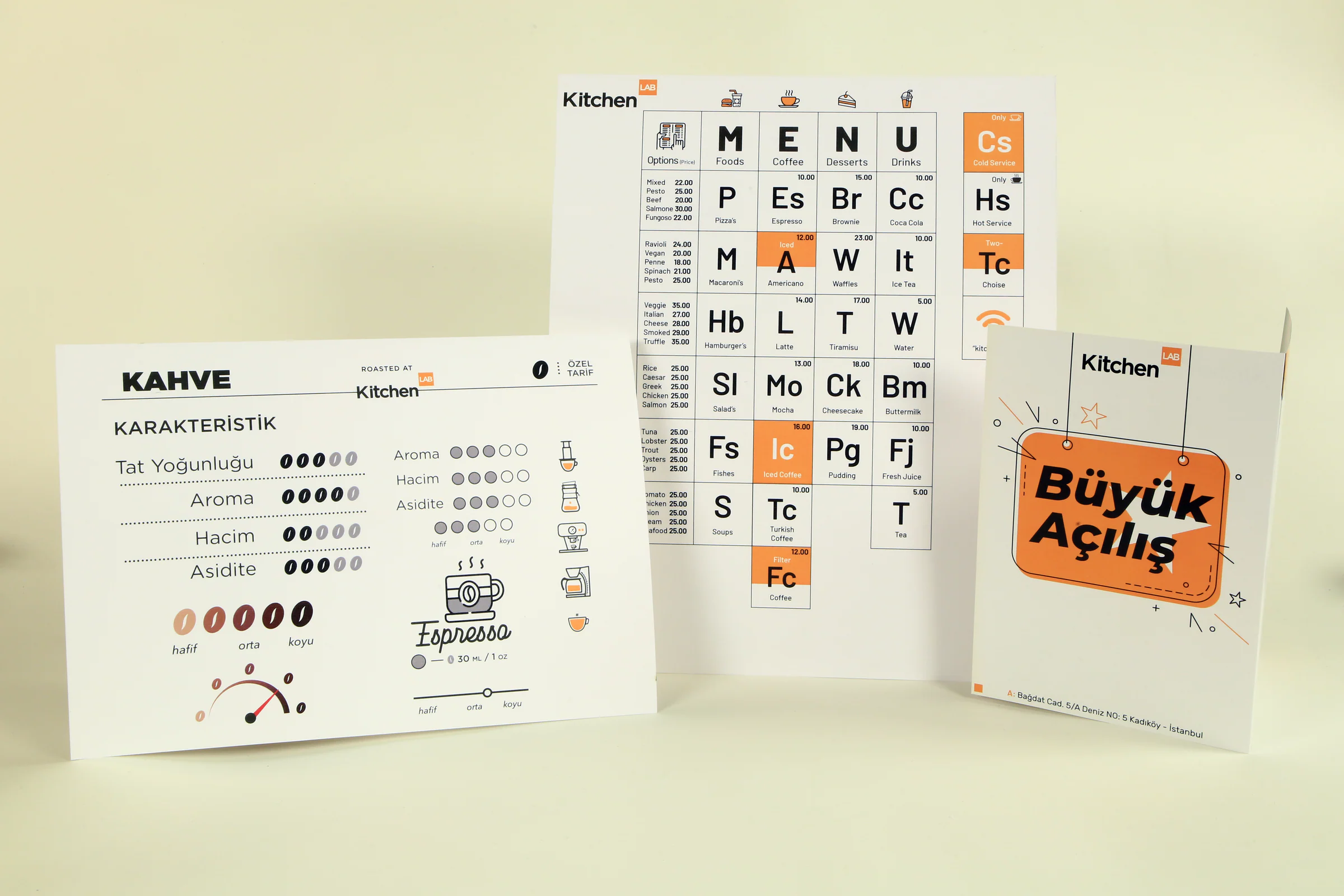 Printed coffee profile card, periodic-table menu and Büyük Açılış opening card standing together on a cream backdrop.